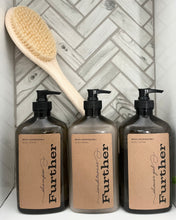 Load image into Gallery viewer, A set of three Further branded bath and shower products, including shampoo, conditioner, and shower gel, displayed with a wooden brush and a tile background.